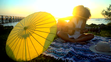 african american girl sunset beach picnic playing guitar