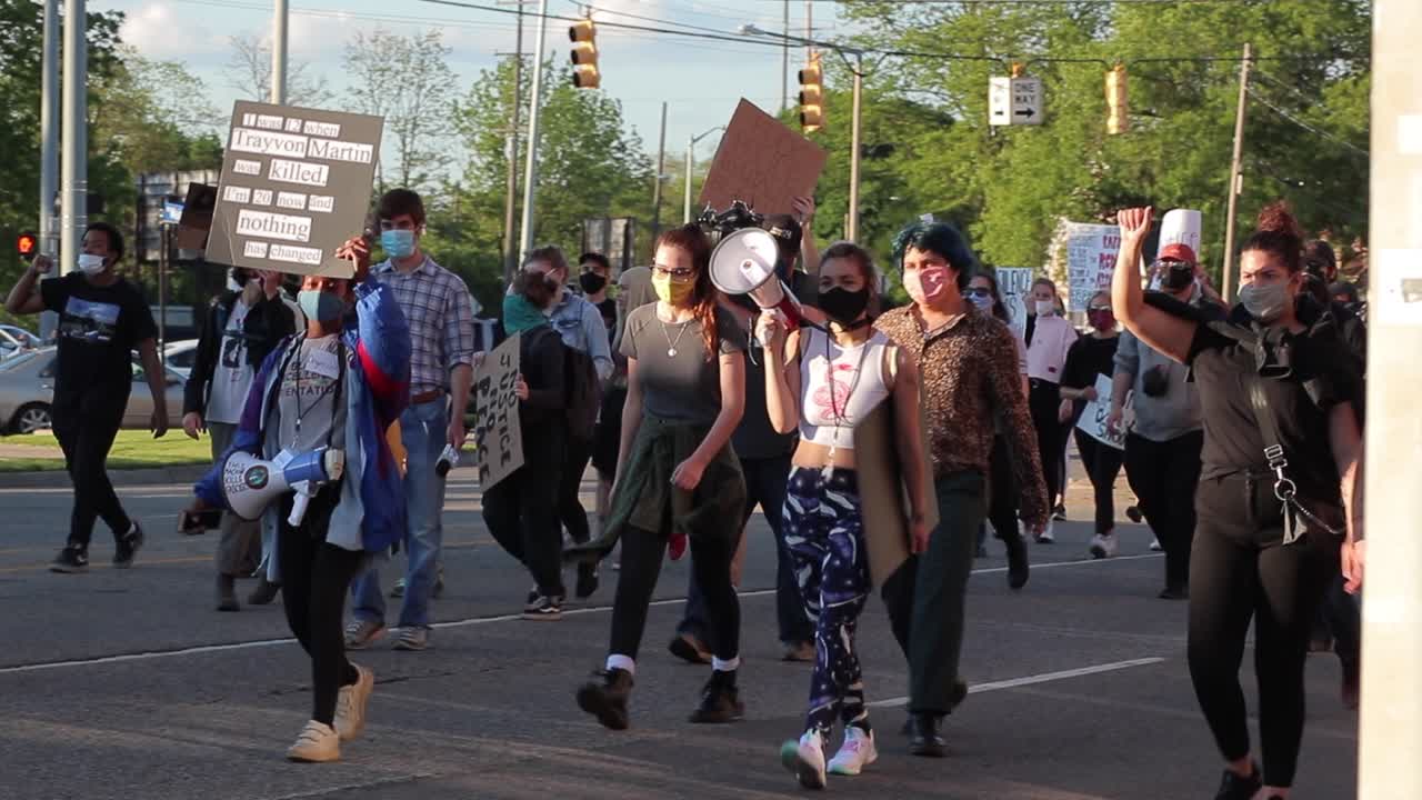 BLM protest marcher in COVID mask, speaks into megaphone while walking