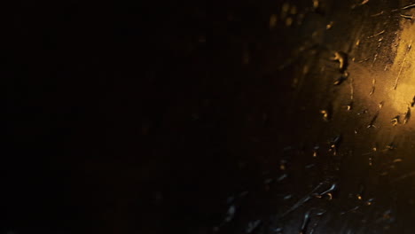 view of moving car window on rainy night. droplets of water