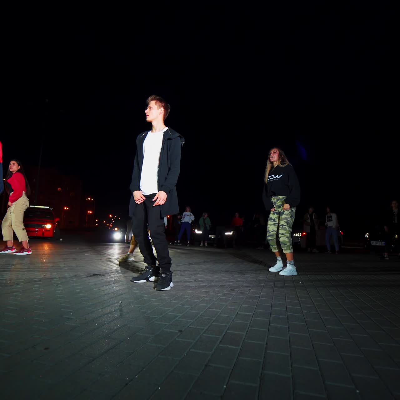 Elegante esibizione di danza notturna tra luci lampeggianti. Gruppo di ballerini che si esibisce in una performance hip hop. Vista dal basso