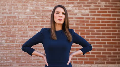 confident professional woman standing against a brick wall