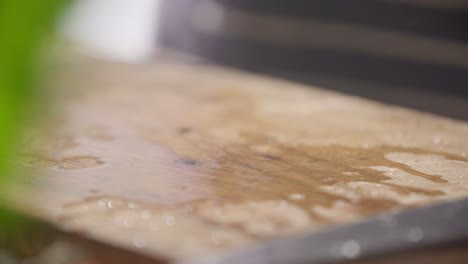 wet chopped green chives falling onto wooden cutting board