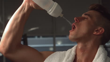 fit muscular man drinking water with towel