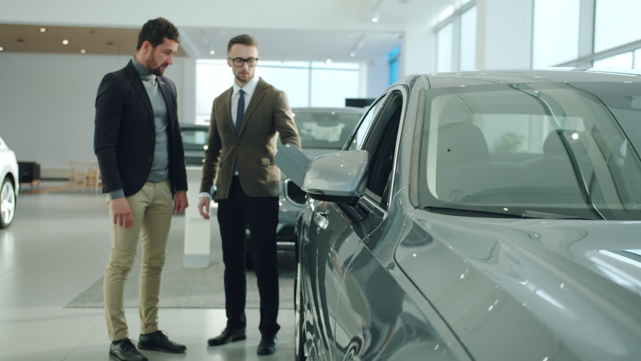 vendedor de coches mostrando el coche al cliente en la sala de exposiciones