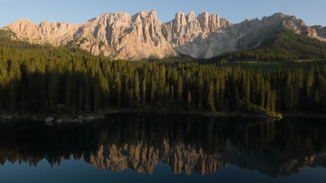 carezza lake with dolomites mountain peak reflection in the background at sunset