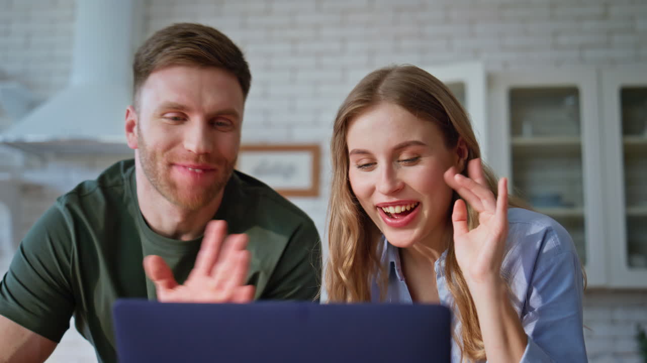 Smiling sweethearts video calling computer in kitchen enjoying together closeup