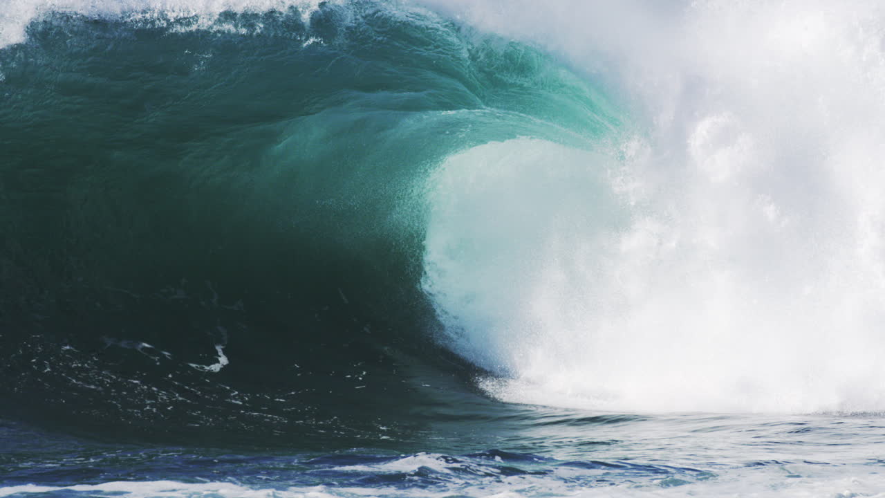 Crashing wave throws spray into the air, light piercing through the thick mist