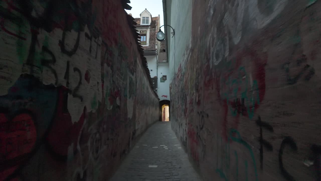 POV walking shot highlighting urban graffiti and confined space along Strada Sforii, Brașov