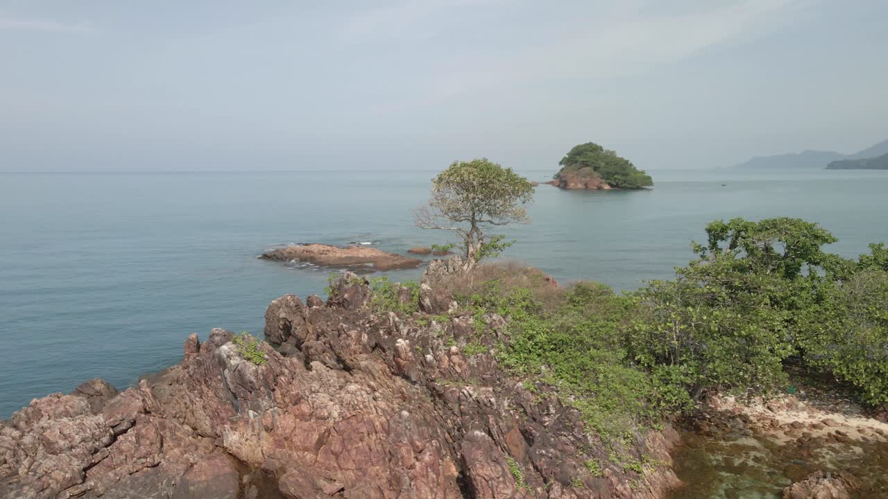 공중 조감도 궤도 무인 항공기는 동남아시아의 작은 황량한 열대 섬을 배경으로 섬을 촬영했습니다.