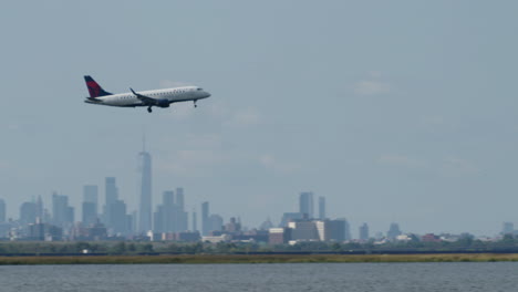 delta plane passes in front of new york city skyline on hazy day with camera panning to follow