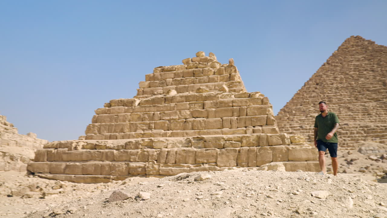 A Tourist Standing Near Giza Necropolis Pyramid Complex During Sunny Day Near Cairo, Egypt. Aerial Orbiting Shot