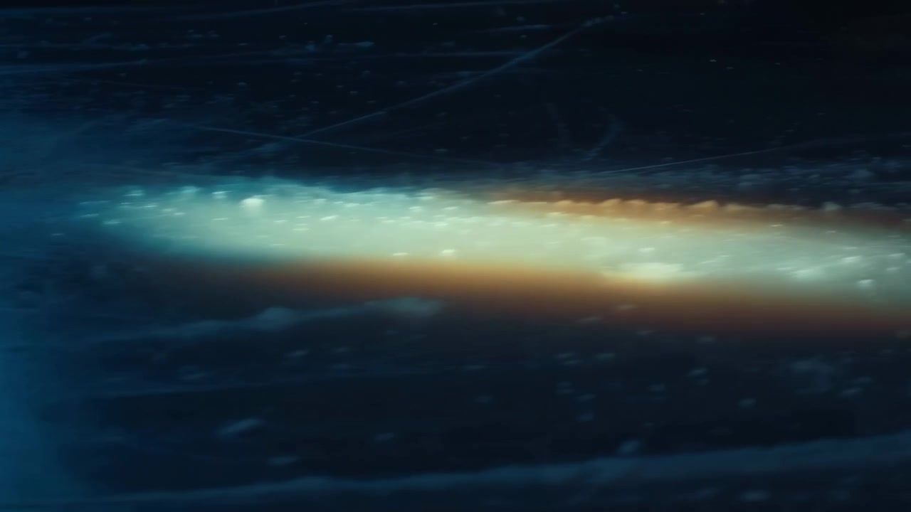 Acqua blu scuro astratta con una striscia turchese brillante che attraversa l'inquadratura, leggere increspature, riflessi luminosi e un aspetto atmosferico suggestivo.