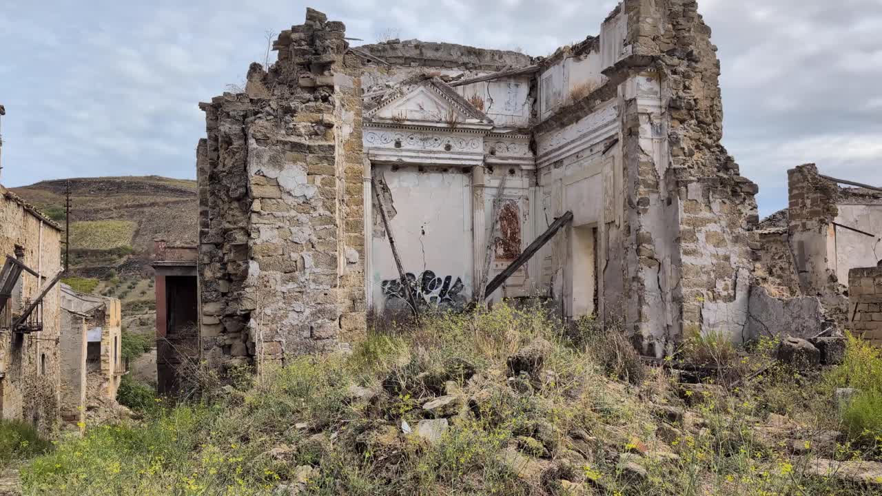 Slow pan left of the abandoned ghost town of Poggioreale in Sicily, Italy, showing earthquake-damaged ruins and overgrown streets of this haunting historical site
