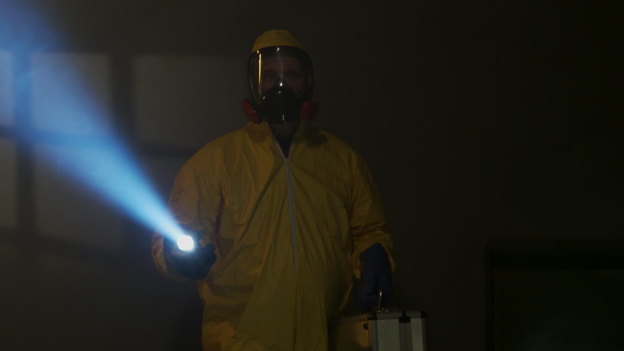 Mann iført hazmat-drakt utforsker et røykfylt rom