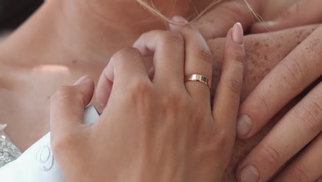 bridegroom with freckles on arms embraces newlywed wife