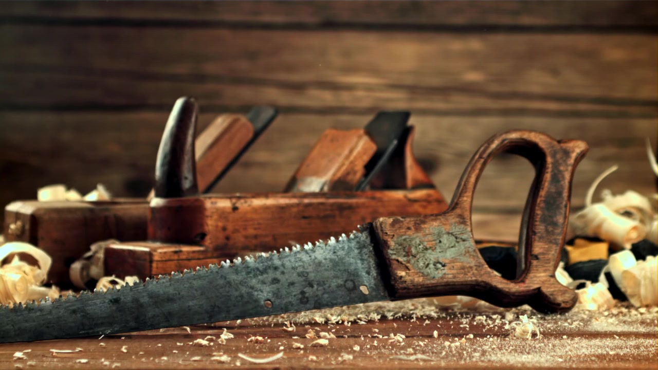 A Vintage Hand Saw Slides onto a Workbench with Wood Shavings