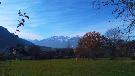 footage-of-an-Austrian-mountain-alps-glacers-from-a-distance-with-green-foreground-and-blue-sky