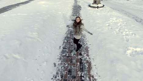 young beautiful girl is circling around herself at the winter path