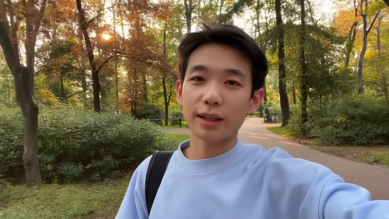Giovane uomo asiatico che fa vlogging e parla in un parco soleggiato