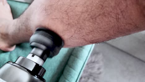 close-up of a person administering a massage gun therapy on their leg muscles.slow motion