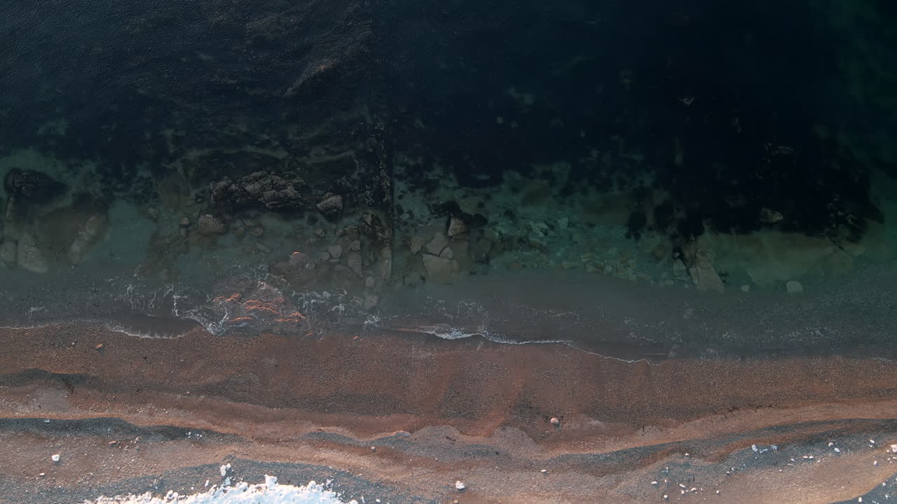 Drone shot looking straight down on a beach in the spring when there is still some snow on the ground