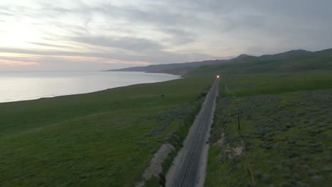 Train-tracks-with-train-approaching-in-the-distance-along-coastline-