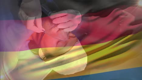 Animation-of-waving-germany-flag-against-doctor-placing-oxygen-mask-on-a-female-patient-at-hospital
