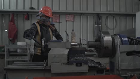 indian working class man work on drill rotary engine mechanical precision machine piercing heavy metal iron steel wearing protective gloves and helmet in asia metallurgic factory