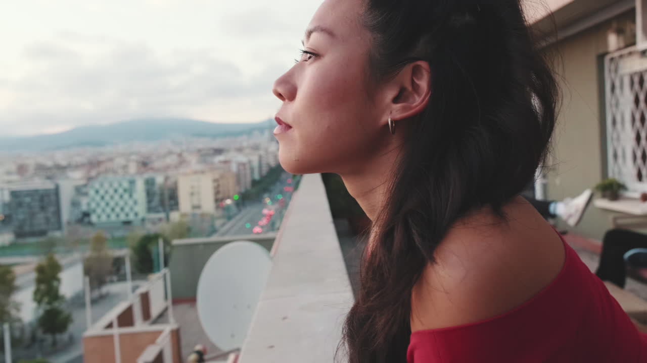 Woman gazing at cityscape from balcony