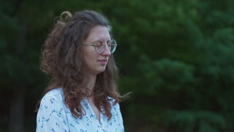 la inclinación de una mujer joven al aire libre, con gafas meditando con los ojos cerrados y muchos mosquitos alrededor