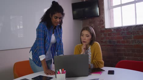 Verschiedene-Weibliche-Geschäftskollegen-Diskutieren-Bei-Der-Arbeit-Und-Schauen-Auf-Den-Laptop