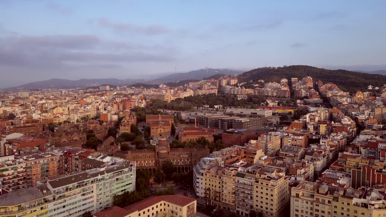 A cinematic drone shot of Barcelona's capital city showcasing modern and old buildings