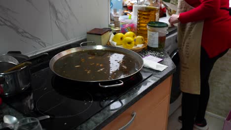 woman seasoning the meal while the rice with black squid ink is being cooked