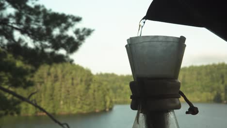 filling chemex and paper coffee filter with water for coffee extraction in canadian northern forest while hiking