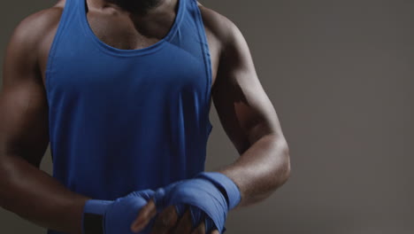 close up of male boxer wrapping hands with protective bandages before boxing match or training session 2