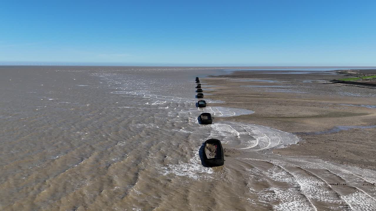 Waves breaking over Barges on River Blackwater Essex UK used for WW2 target practice