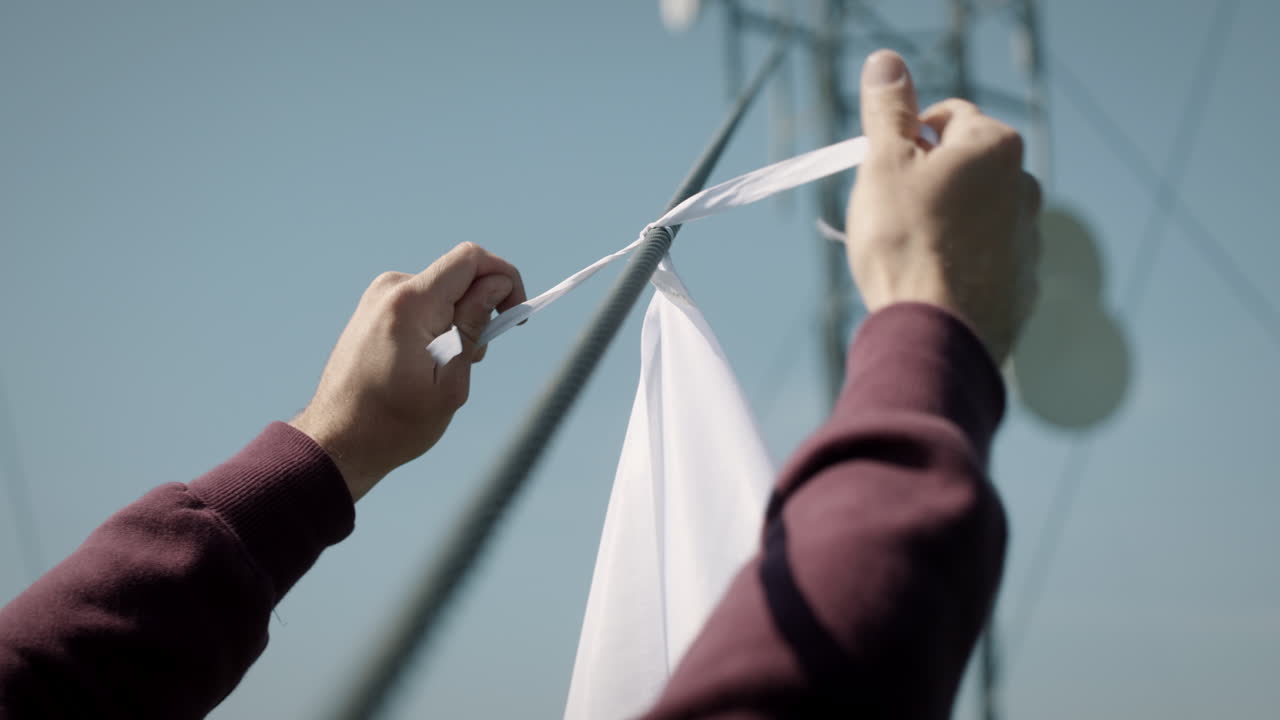 руки молодого человека, повязывающего словенский флаг на кабельном