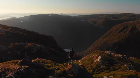 man walking at the end of a cliff, enjoying the landscape - aerial 4k