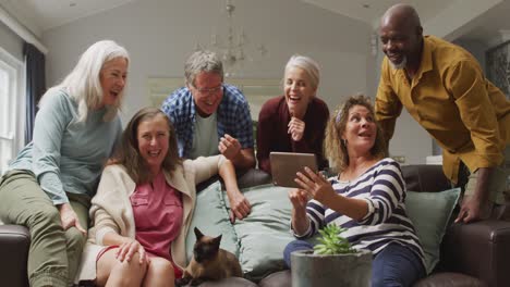 animación de felices y diversas amigas y amigos mayores usando tableta en casa