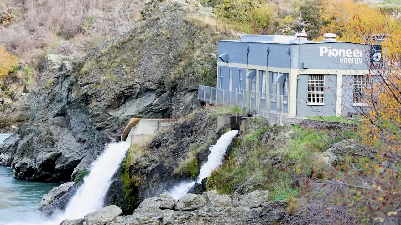 Hydroelectric station with cascading waterfall in a rocky landscape. Bright lighting highlights the natural and industrial elements