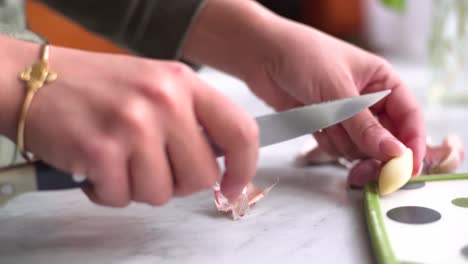 hand peeling garlic next to a sea bream and a whiting on the work surface