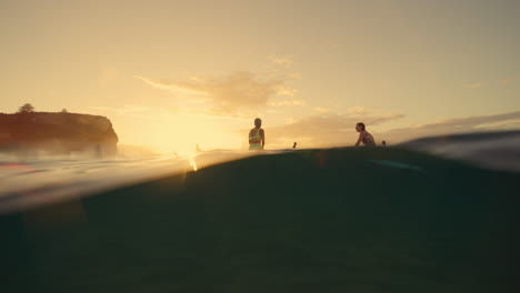 las mujeres surfistas hablan mientras surfean en la playa de arena en la luz de la mañana