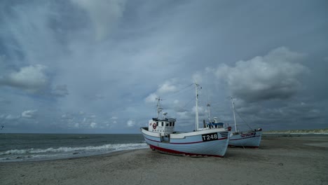 timelapse de nubes moviéndose sobre dos barcos de pescadores en una playa