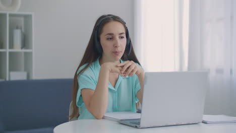 Operadora-Femenina-En-El-Trabajo-Del-Centro-De-Llamadas.-Mujer-De-Negocios-Joven-Con-Auriculares-Comunicándose-Por-Videollamada.-Mujer-De-Negocios-Hablando-Mirando-Una-Computadora-Portátil-Conferencia-En-Línea-Chat-De-Oficina-A-Distancia