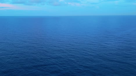 Light-blue-sky-blends-into-cerulean-Caribbean-dark-blue-ocean-water,-drone-static