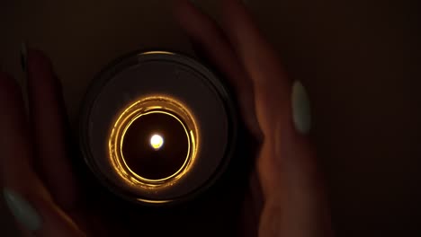 la vela arde atmosféricamente en las manos de una chica con una hermosa manicura.