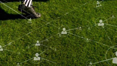 Animation-of-network-of-connections-with-people-icons-over-football-player-kicking-ball