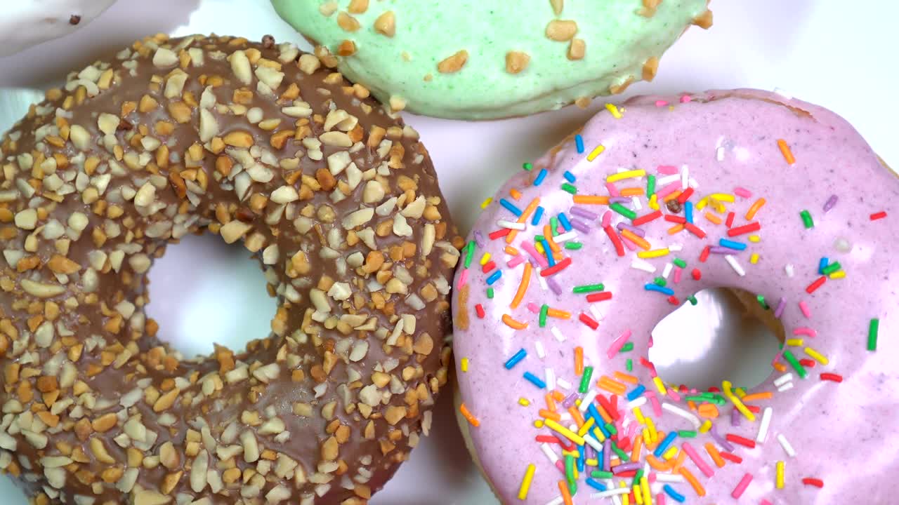muchas rosquillas brillantes y coloridas rosquillas, tiro macro, girando lentamente en una placa giratoria