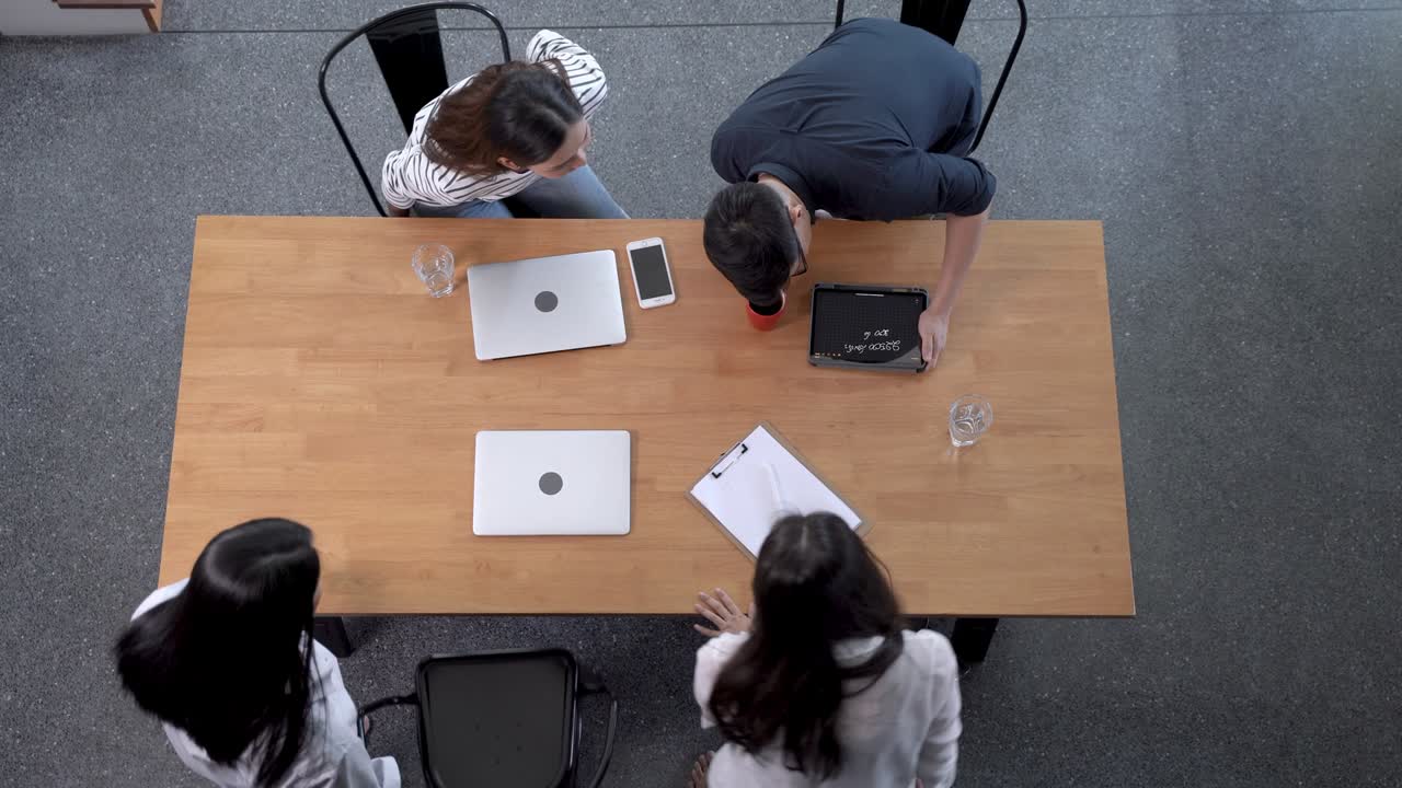 Top view of four  business people sitting at desk and discussing project during meeting in office. Concept business life and technology.