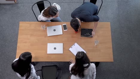 top view of four  business people sitting at desk and discussing project during meeting in office. concept business life and technology.